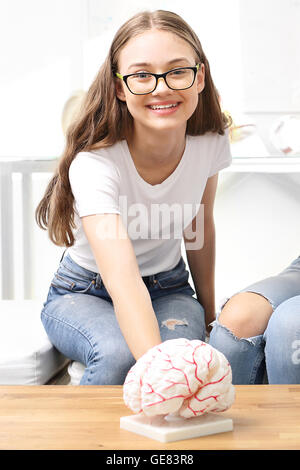 Schoolgirl watching model of the human brain. Stock Photo