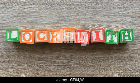 Wood blocks or wooden cubes toys with alphabet letters on them combined together to create the word LOCKSMITH Stock Photo