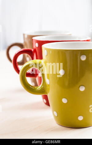 Three colored cups standing in a row. Stock Photo