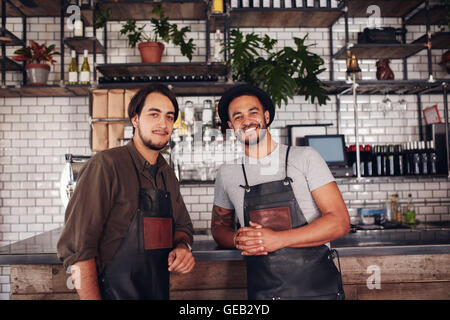 Portrait of two young coffee shop owners at the counter. Cafe partners standing together and looking at camera. Stock Photo