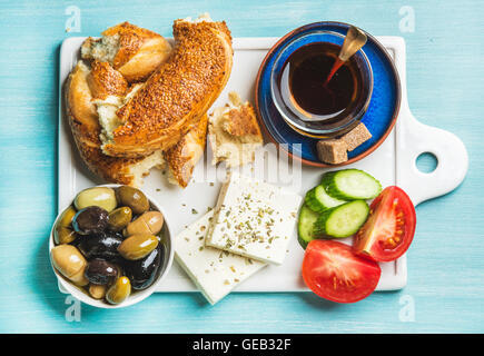 Turkish traditional breakfast with feta cheese, vegetables, olives, simit bagel and tea