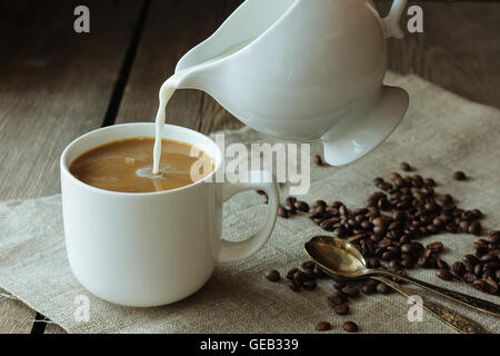 Milk pouring in the cup of coffee selective focus Stock Photo