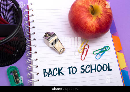 School supplies with red apple on a purple background. Stock Photo