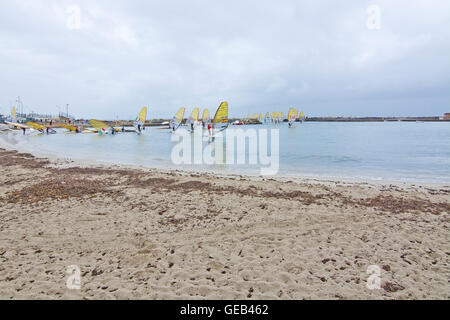 Windsurfers in yellow sails take off at an International windsurfing competition in rainy weather in Playa de Palma, Mallorca. Stock Photo