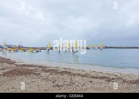 Windsurfers in yellow sails take off at an International windsurfing competition in rainy weather in Playa de Palma, Mallorca. Stock Photo