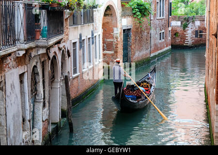 Gondolier rowing his gondola carrying tourists on a canal Venice Italy Stock Photo