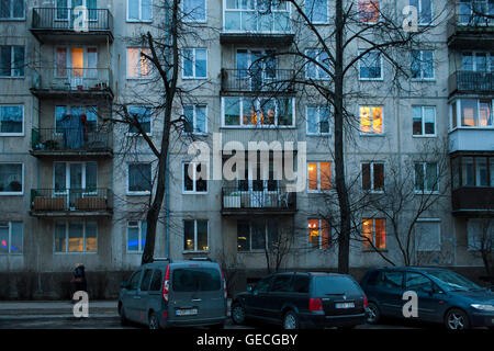 Cars parked out front of a typical soviet era style apartment blocks at dusk on the city streets in Vilnius Lithuania Stock Photo