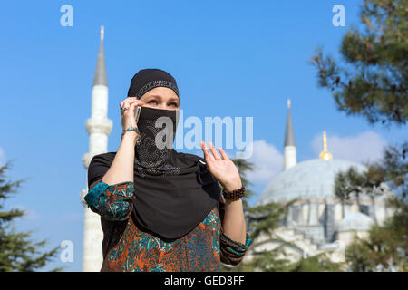 Portrait of beautiful Arabian Woman in traditional Muslim Clothing talking on Telephone gesturing Middle East Urban landscape wi Stock Photo