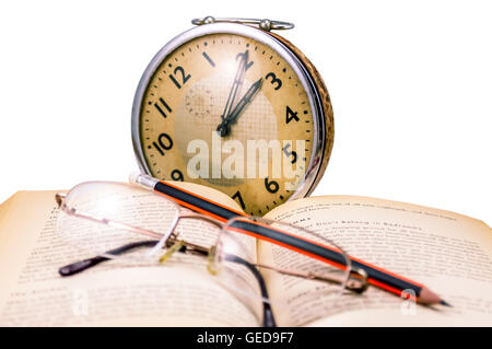 book glasses, pencil an old clock -  reading in old age. Stock Photo