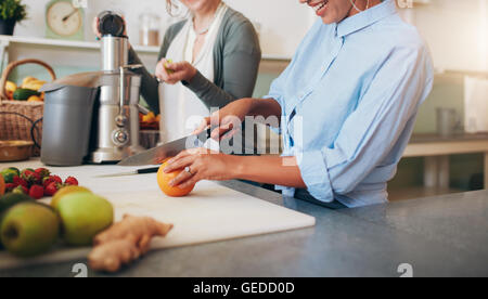 Cropped image of woman cutting an orange. Women at bar counter preparing juice. Stock Photo