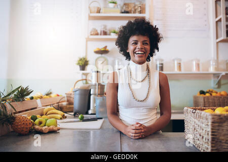 Portrait of young african woman standing behind juice bar counter looking at camera and smiling. Happy juice bar owner. Stock Photo