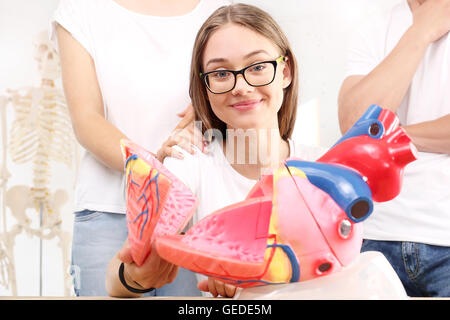 Schoolgirl on lesson biology watching model of the human heart Stock Photo