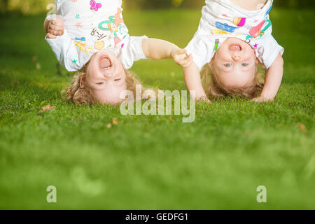 The two little baby girls hanging upside down Stock Photo