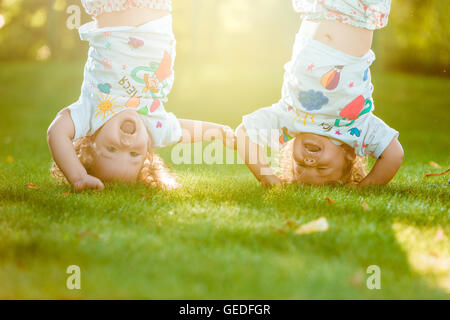 The two little baby girls hanging upside down Stock Photo