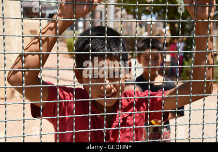 A boy looks into Arizona from Mexico at the border between Naco, Arizona, USA and Naco, Sonora, Mexico at the port-of-entry. Stock Photo