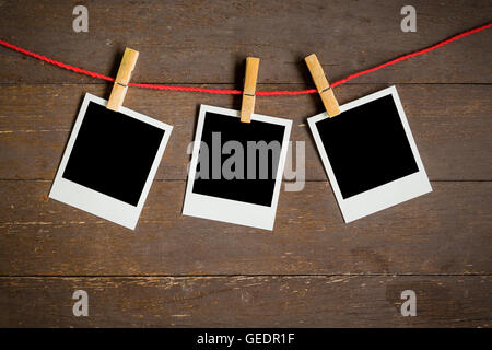 three blank photo frame hanging on wood background with space Stock Photo