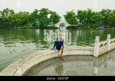 Tourist at the traditional stone arch brdge on Banyan Lake, Guilin, Guangxi Autonomous Region, China Stock Photo