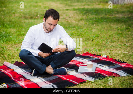 handsome young businessman reading book lying in the park Stock Photo