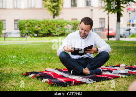 handsome young businessman reading book lying in the park Stock Photo