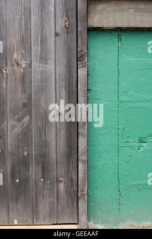 A wooden panel wall beside a green painted concrete wall for backgrounds Stock Photo