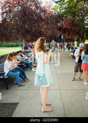 People of all ages and backgrounds are transfixed on their mobile devices, playing Pokemon Go (Pokémon Go). Stock Photo