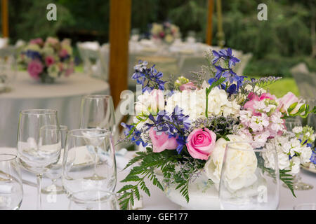 Flower arrangements on tables with glasses at wedding. Stock Photo