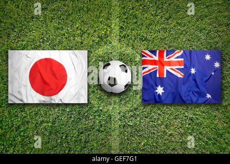 Japan vs. Australia flags on green soccer field Stock Photo