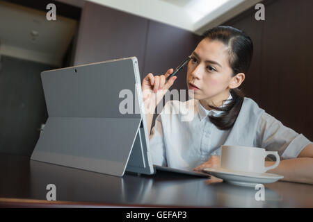 business woman thinking new idea work plan, hold pen on hand. sitting using tablet Laptop Computer. Stock Photo