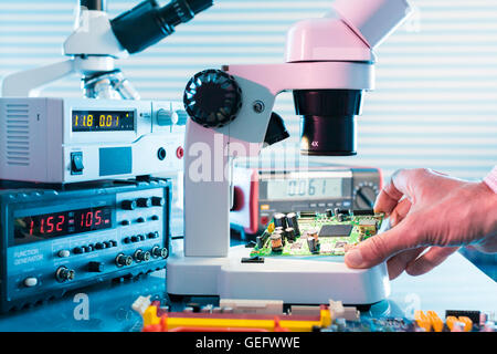 Microelectronics laboratory with the measuring instruments and microscopes. Electronic circuit board in hand Stock Photo