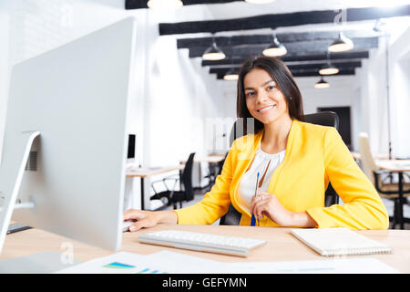 Portrait of a smiling young businesswoman using laptop in office Stock Photo