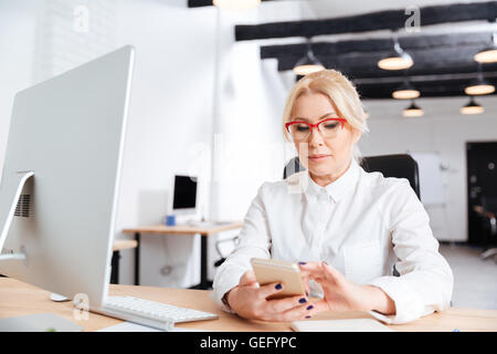 Beautiful mature woman using smart phone in the office Stock Photo