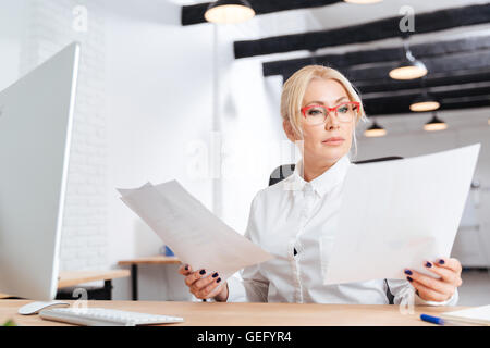 Attractive pensive mature businesswoman reading papers in office Stock Photo