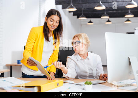 Two smiling businesswomen working together with pc at the table in office Stock Photo