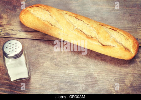 Vintage toned fresh baguette on wooden table, close up Stock Photo