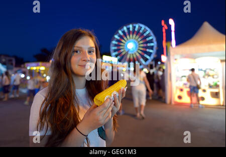 teen girl eating corn in fair Stock Photo