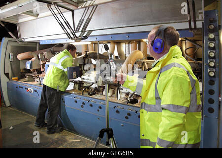 An environmental engineer monitors noise levels next to a timber cutting machine at a UK manufacturing plant Stock Photo