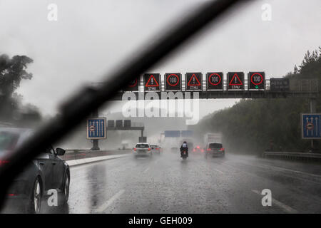car drives, during a heavy rain storm on a highway, windshield wipers on, lot of water on the roadway, Germany, Stock Photo