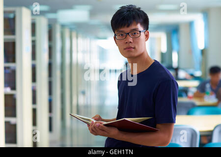 One young male asian or Chinese college students looking at camera smile in the library Stock Photo