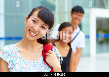three happy young Chinese or asian college students looking at camera ...