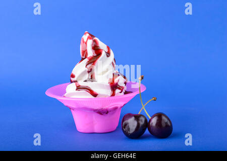 frozen yogurt with black cherry cream and cherry topping on blue background Stock Photo