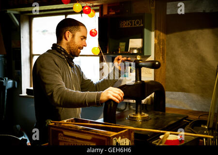 A man using a printing press to create linocut printed signs. Stock Photo
