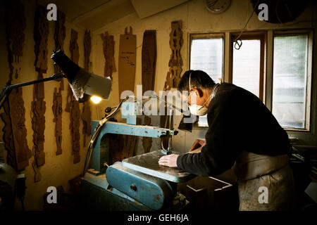 A man working in a furniture maker's workshop, using a machine saw. Stock Photo