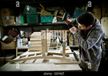 A man working in a furniture maker's workshop assembling a chair. Stock Photo