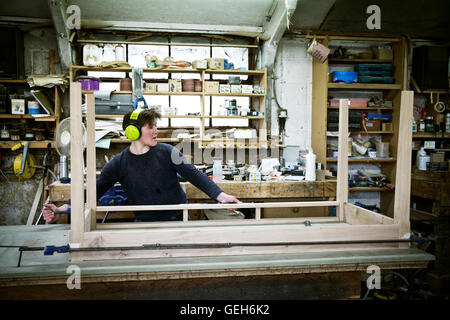 A woman working in a furniture maker's workshop, assembling a table. Stock Photo