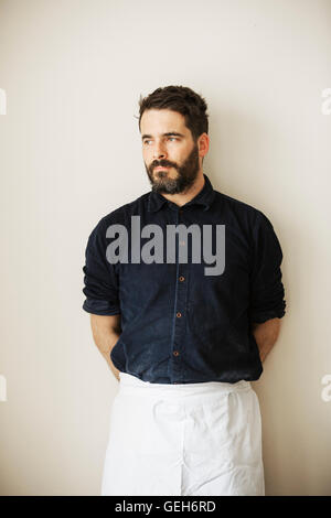 Half length portrait of a bearded man wearing a white apron. Stock Photo