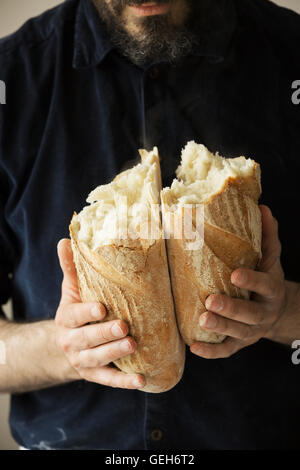 Close up of a baker holding two freshly baked loaves of bread. Stock Photo