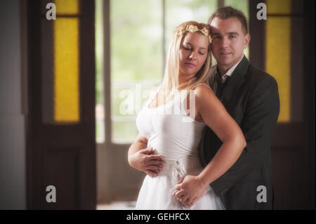 Groom holding the bride by her waist and hands in a dreamy pose Stock Photo