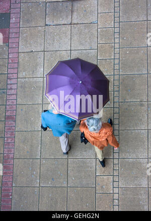 Senior couple sharing the umbrella while walking down the wet sidewalk in the center of Belgrade, Serbia, on May, 14th 2016. Dec Stock Photo