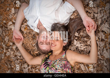 Man and woman hold hands lying on the floor face to face in opposite directions Stock Photo