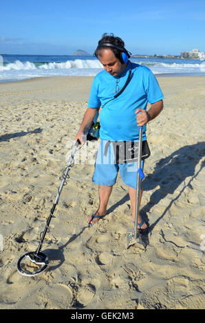 Rio de Janeiro, Brazil. 08th July, 2016. Carlos Saman uses a metal detector to look for objects tourists have lost in the shade of the Copacabana Palace hotel on the beach of Copacabana in Rio de Janeiro, Brazil, 08 July 2016. Photo: GEORG ISMAR/dpa/Alamy Live News Stock Photo